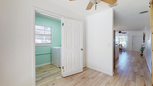 hall with washer / clothes dryer, plenty of natural light, and light hardwood / wood-style flooring