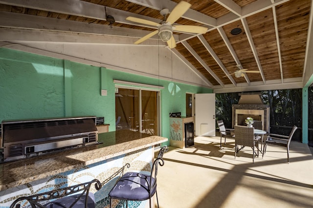 interior space with a grill, ceiling fan, an outdoor kitchen, and exterior fireplace