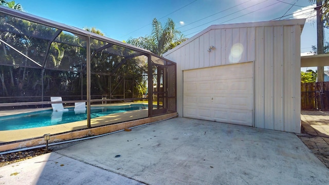 view of swimming pool featuring an outbuilding, glass enclosure, and a garage