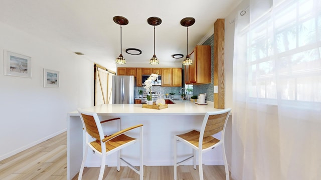 kitchen with kitchen peninsula, appliances with stainless steel finishes, backsplash, sink, and hanging light fixtures