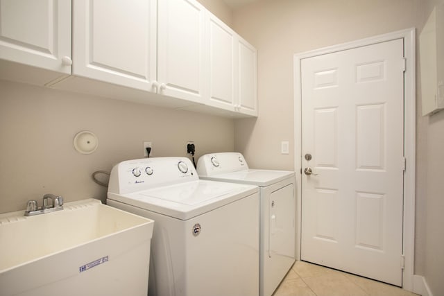 clothes washing area with light tile patterned floors, independent washer and dryer, a sink, and cabinet space