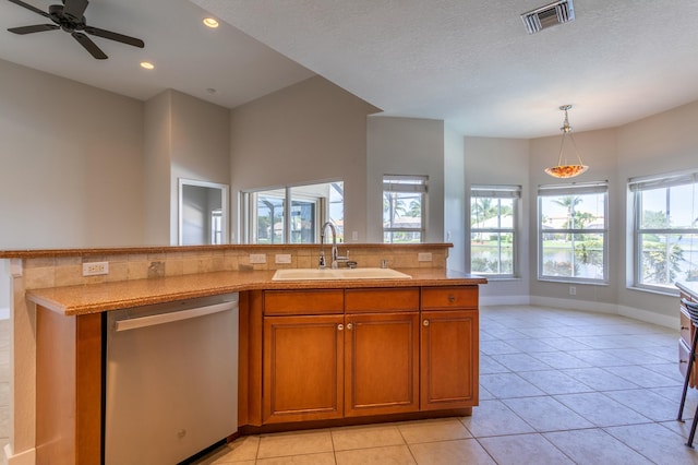 kitchen with light countertops, visible vents, brown cabinetry, a sink, and dishwasher