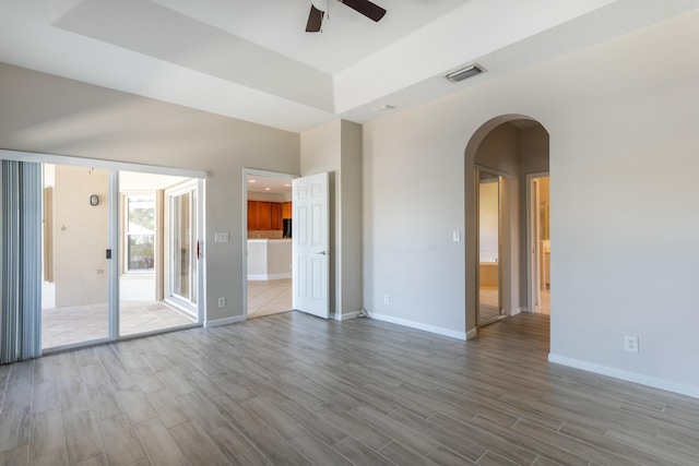 empty room featuring dark wood-style floors, baseboards, and arched walkways