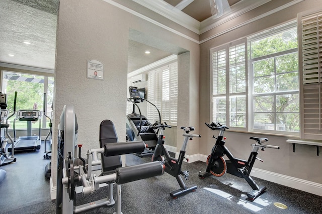 gym featuring a textured ceiling, a textured wall, a wall unit AC, baseboards, and crown molding