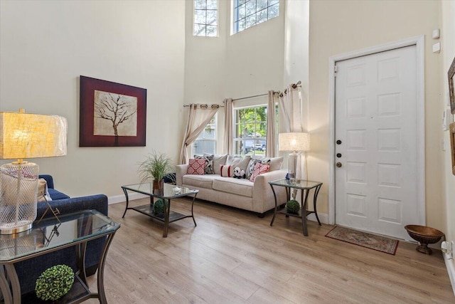 living room with light hardwood / wood-style floors and a towering ceiling