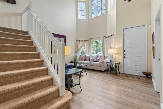 living room featuring a towering ceiling and light hardwood / wood-style flooring