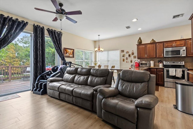 living room with light hardwood / wood-style floors and ceiling fan with notable chandelier