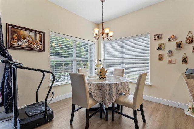 dining space with light hardwood / wood-style floors and an inviting chandelier