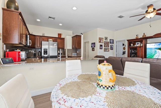 dining room featuring ceiling fan, light wood-type flooring, and sink