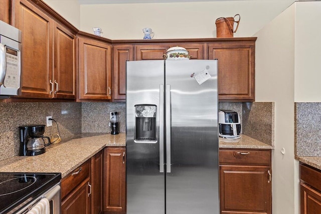 kitchen featuring light stone counters, stainless steel fridge with ice dispenser, and tasteful backsplash