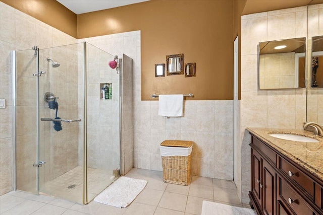 bathroom featuring tile patterned floors, vanity, tile walls, and walk in shower