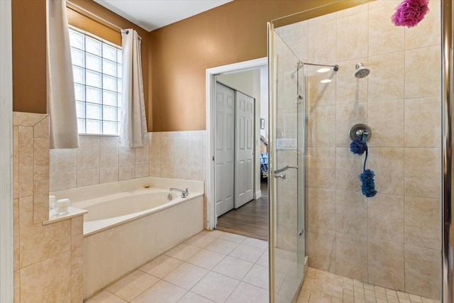 bathroom with tile patterned flooring, a wealth of natural light, independent shower and bath, and tile walls