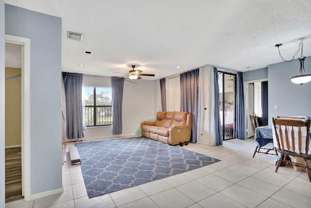 living room with ceiling fan, light tile patterned floors, and a textured ceiling