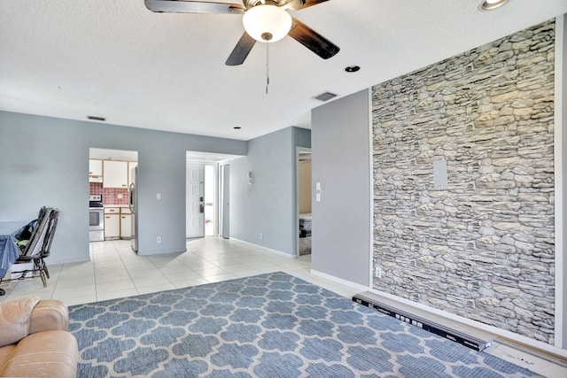 unfurnished living room with a textured ceiling, ceiling fan, and light tile patterned flooring