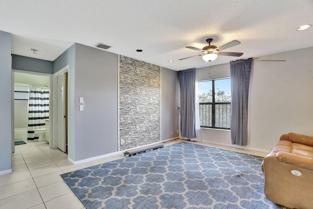 living area with ceiling fan, light tile patterned floors, and a textured ceiling