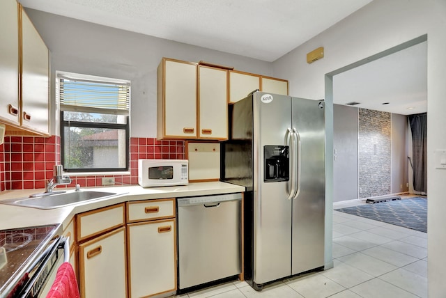 kitchen featuring white cabinetry, sink, backsplash, light tile patterned floors, and appliances with stainless steel finishes