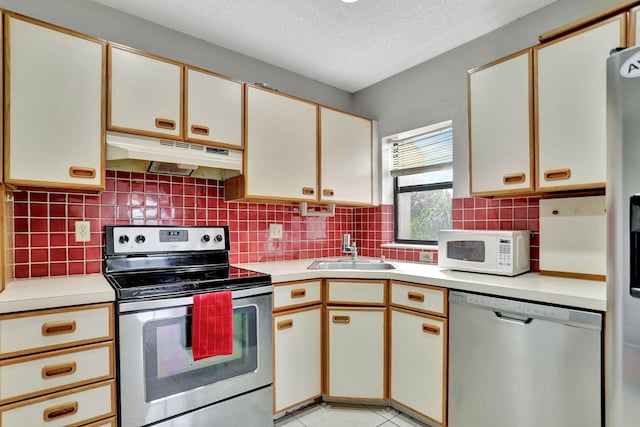 kitchen featuring a textured ceiling, stainless steel appliances, sink, white cabinetry, and light tile patterned flooring