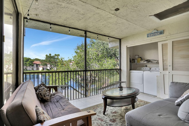 sunroom / solarium featuring separate washer and dryer and a water view