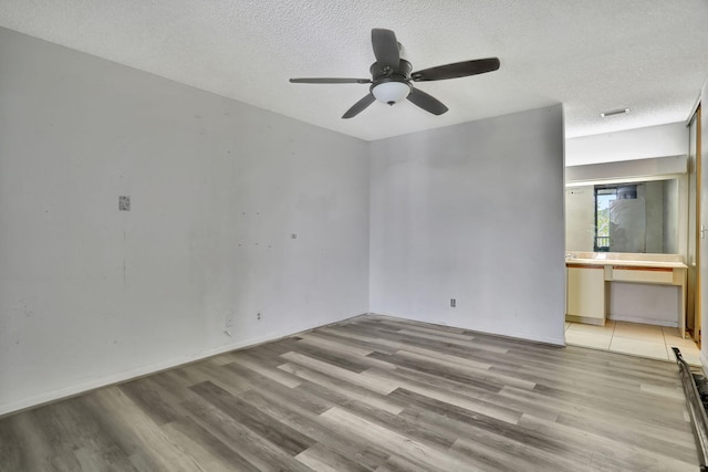 unfurnished living room with a textured ceiling, light hardwood / wood-style floors, and ceiling fan