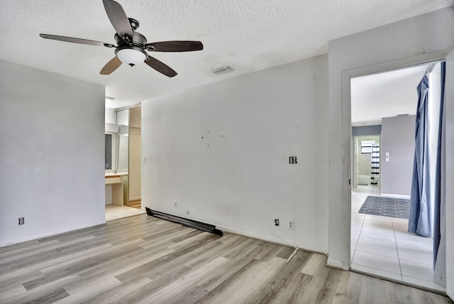 empty room featuring a textured ceiling, light wood-type flooring, and ceiling fan