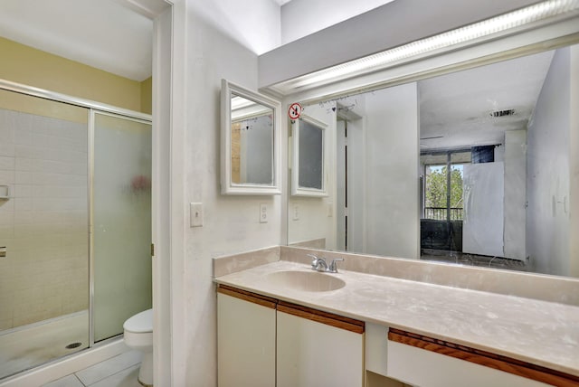 bathroom with tile patterned floors, vanity, an enclosed shower, and toilet