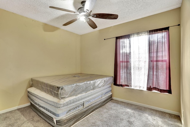 carpeted bedroom featuring ceiling fan and a textured ceiling