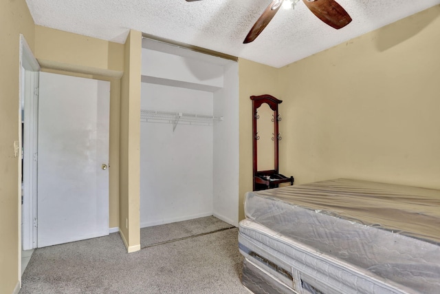 bedroom featuring ceiling fan, a closet, light colored carpet, and a textured ceiling