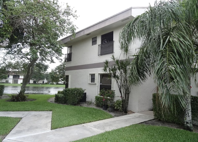 view of side of property with a water view, a yard, and a balcony