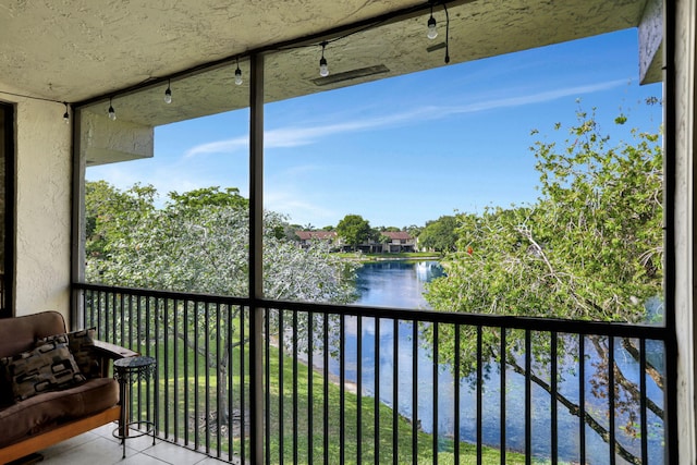 sunroom / solarium with a water view and track lighting