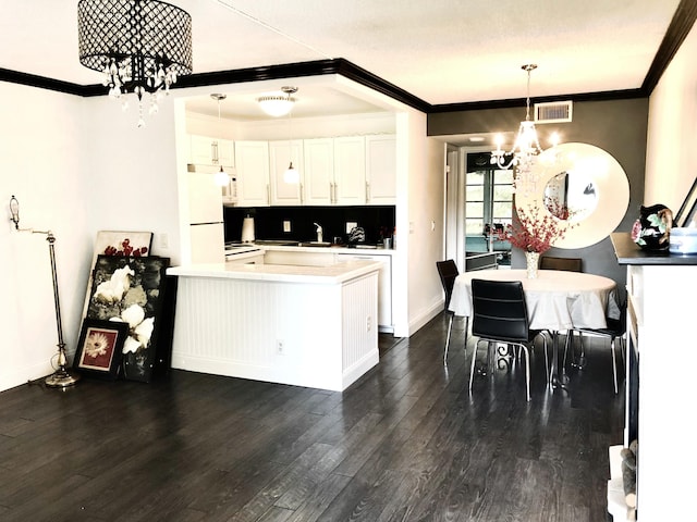 kitchen with dark wood-type flooring, an inviting chandelier, white cabinets, crown molding, and decorative light fixtures