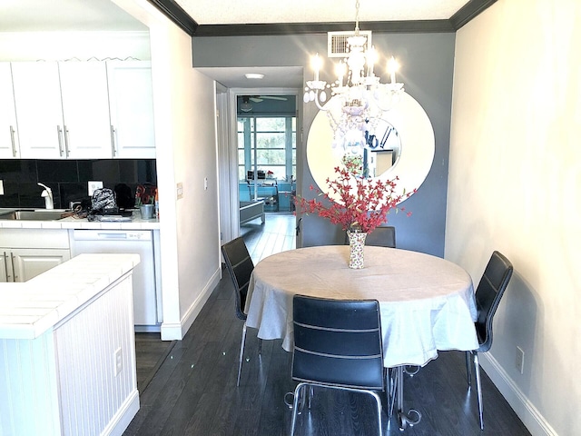 dining space with dark hardwood / wood-style floors, an inviting chandelier, ornamental molding, and sink