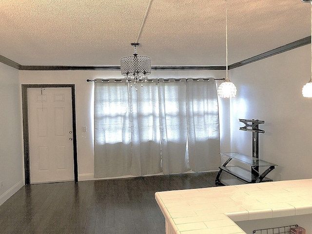 dining space featuring dark hardwood / wood-style flooring, ornamental molding, a textured ceiling, and an inviting chandelier