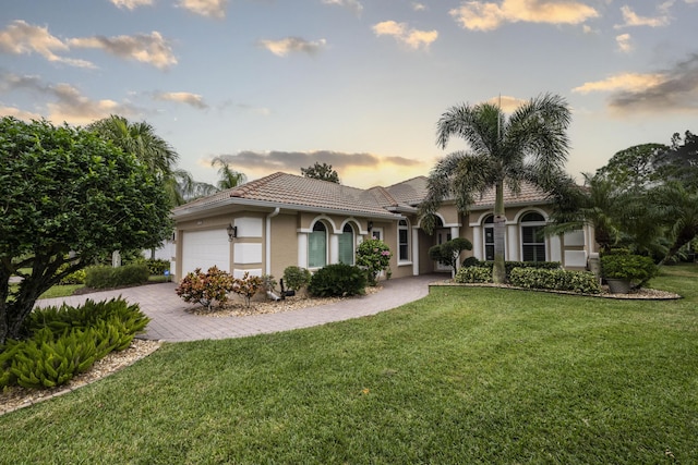 mediterranean / spanish home featuring a garage and a lawn