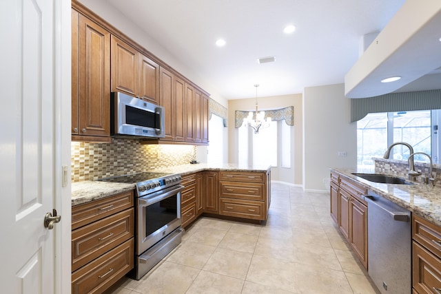 kitchen with stainless steel appliances, backsplash, a chandelier, light stone counters, and sink