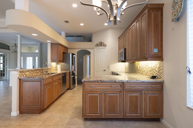 kitchen featuring appliances with stainless steel finishes, kitchen peninsula, a notable chandelier, and sink