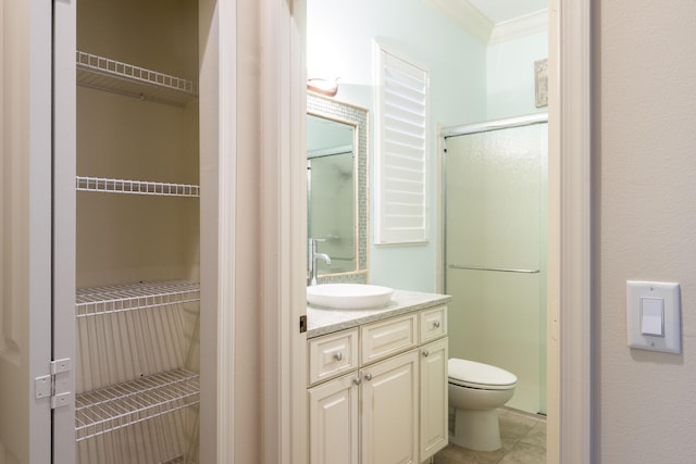 bathroom with toilet, vanity, a shower with door, and crown molding