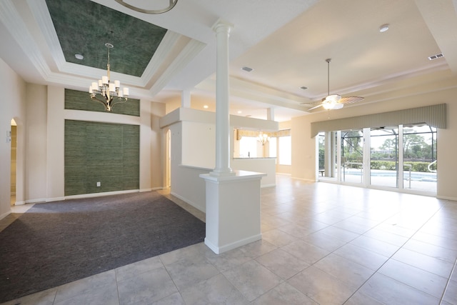 tiled empty room featuring ornate columns, ceiling fan with notable chandelier, and a raised ceiling