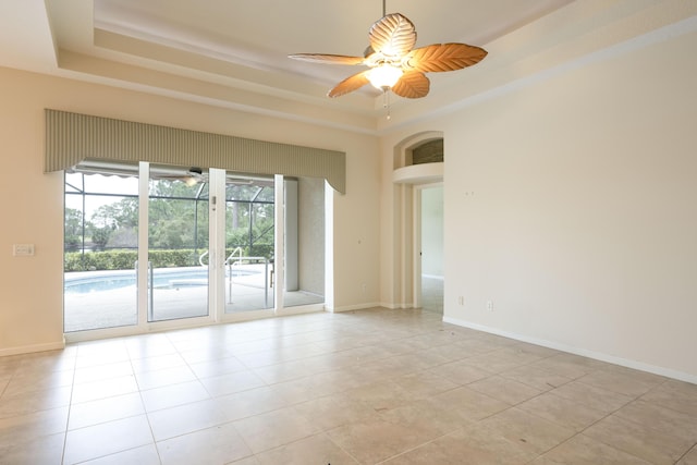 spare room featuring ceiling fan, light tile patterned floors, and a tray ceiling