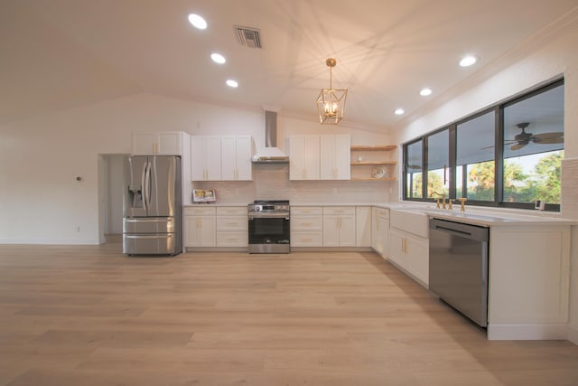 kitchen featuring wall chimney exhaust hood, decorative light fixtures, decorative backsplash, white cabinets, and appliances with stainless steel finishes