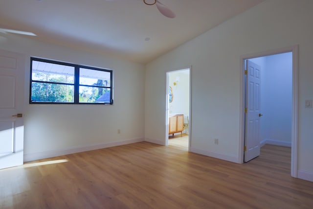 unfurnished bedroom with connected bathroom, a spacious closet, ceiling fan, light hardwood / wood-style flooring, and vaulted ceiling