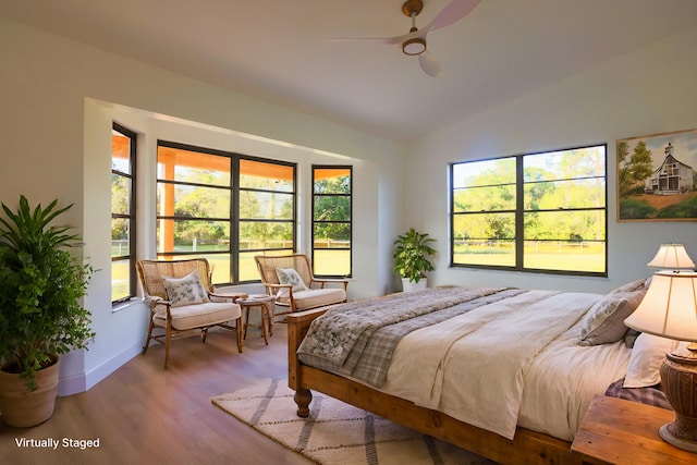 bedroom featuring hardwood / wood-style floors, ceiling fan, multiple windows, and vaulted ceiling