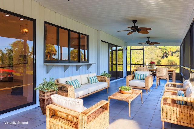 sunroom featuring ceiling fan with notable chandelier