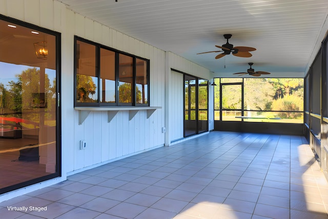 unfurnished sunroom with ceiling fan with notable chandelier