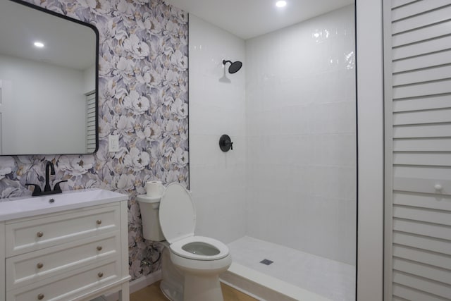 bathroom with tiled shower, vanity, and toilet