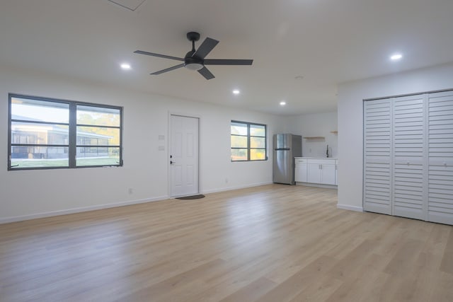 unfurnished living room featuring a wealth of natural light, ceiling fan, and light wood-type flooring