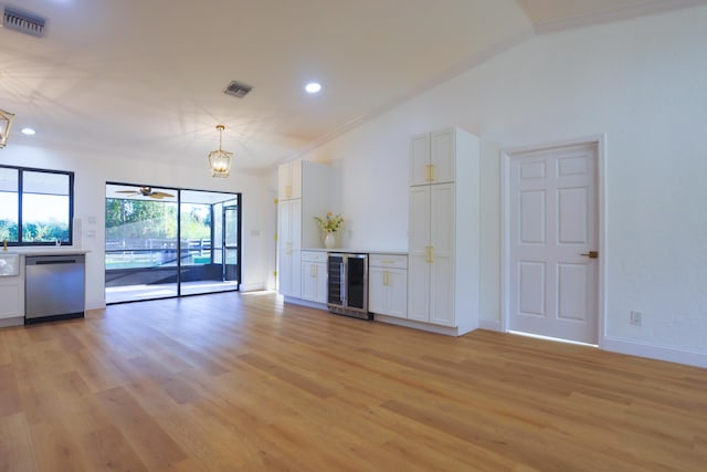 unfurnished living room featuring ceiling fan with notable chandelier, crown molding, vaulted ceiling, light hardwood / wood-style floors, and beverage cooler