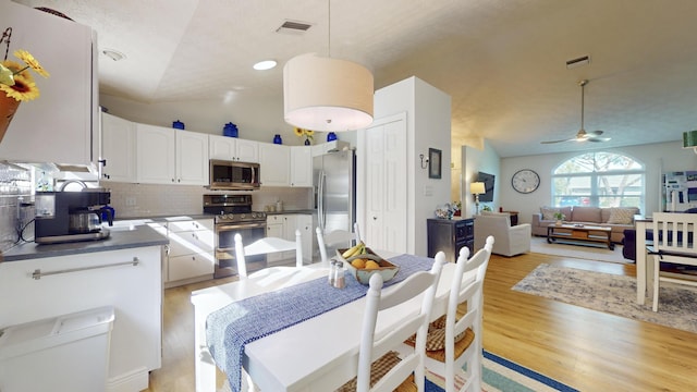 dining area with ceiling fan, light wood-type flooring, and vaulted ceiling