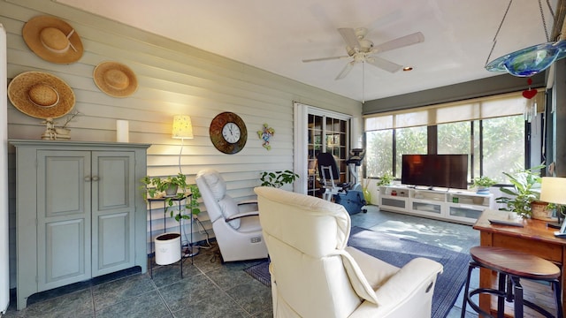 living room featuring ceiling fan and wooden walls