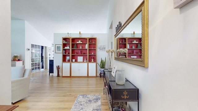 corridor featuring vaulted ceiling and light hardwood / wood-style flooring