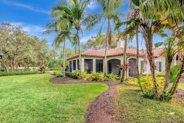 mediterranean / spanish-style house with a sunroom and a front lawn